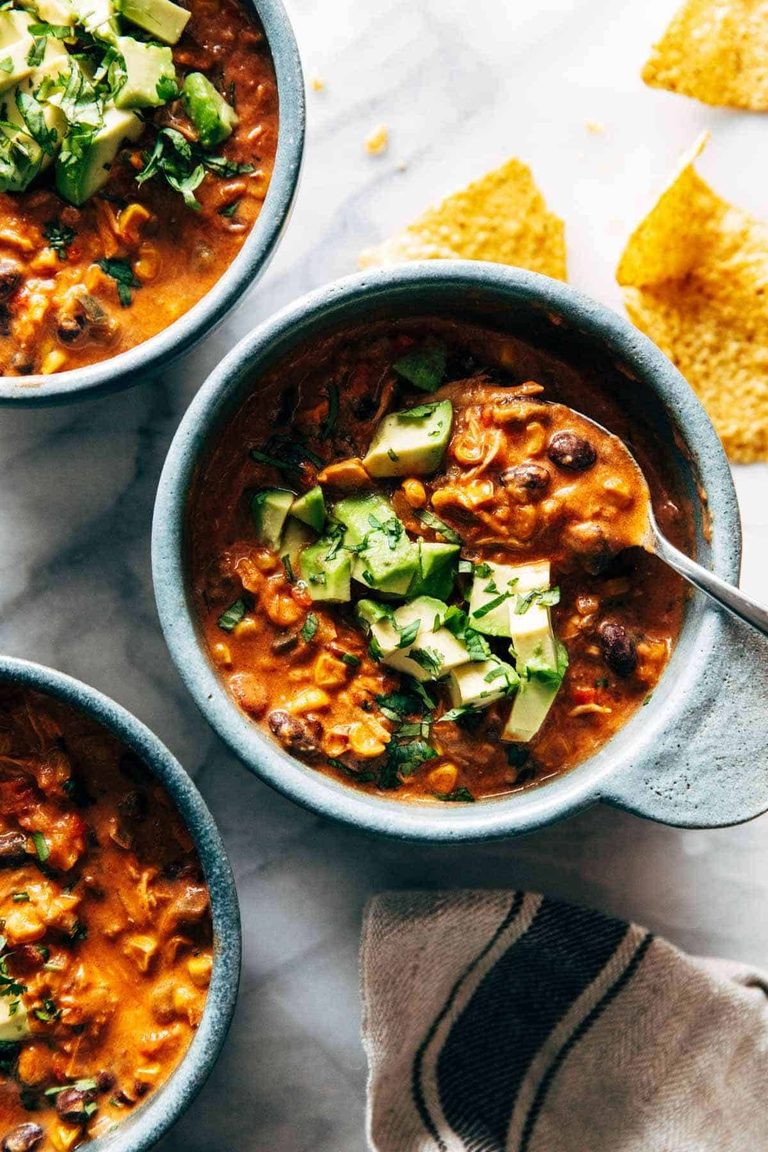 Queso chicken chili in a bowl with avocado on top.