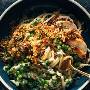 Bucatini pasta in a bowl with a fork and peas