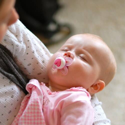 Sleeping infant girl wearing a pink outfit.