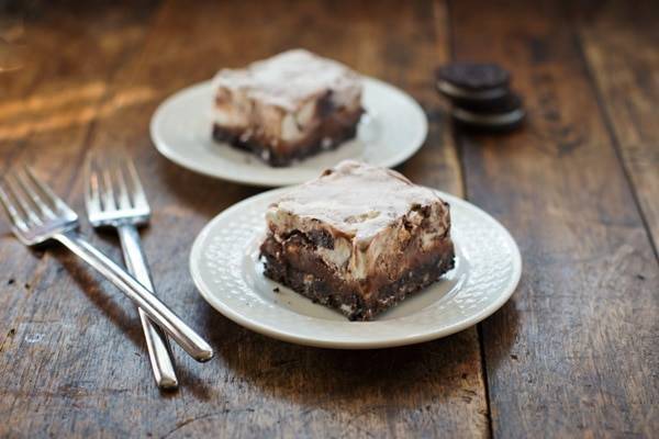 Two Oreo fudge ice cream bars on white plates.