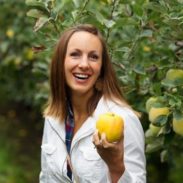 A woman holding up an Opal apple.