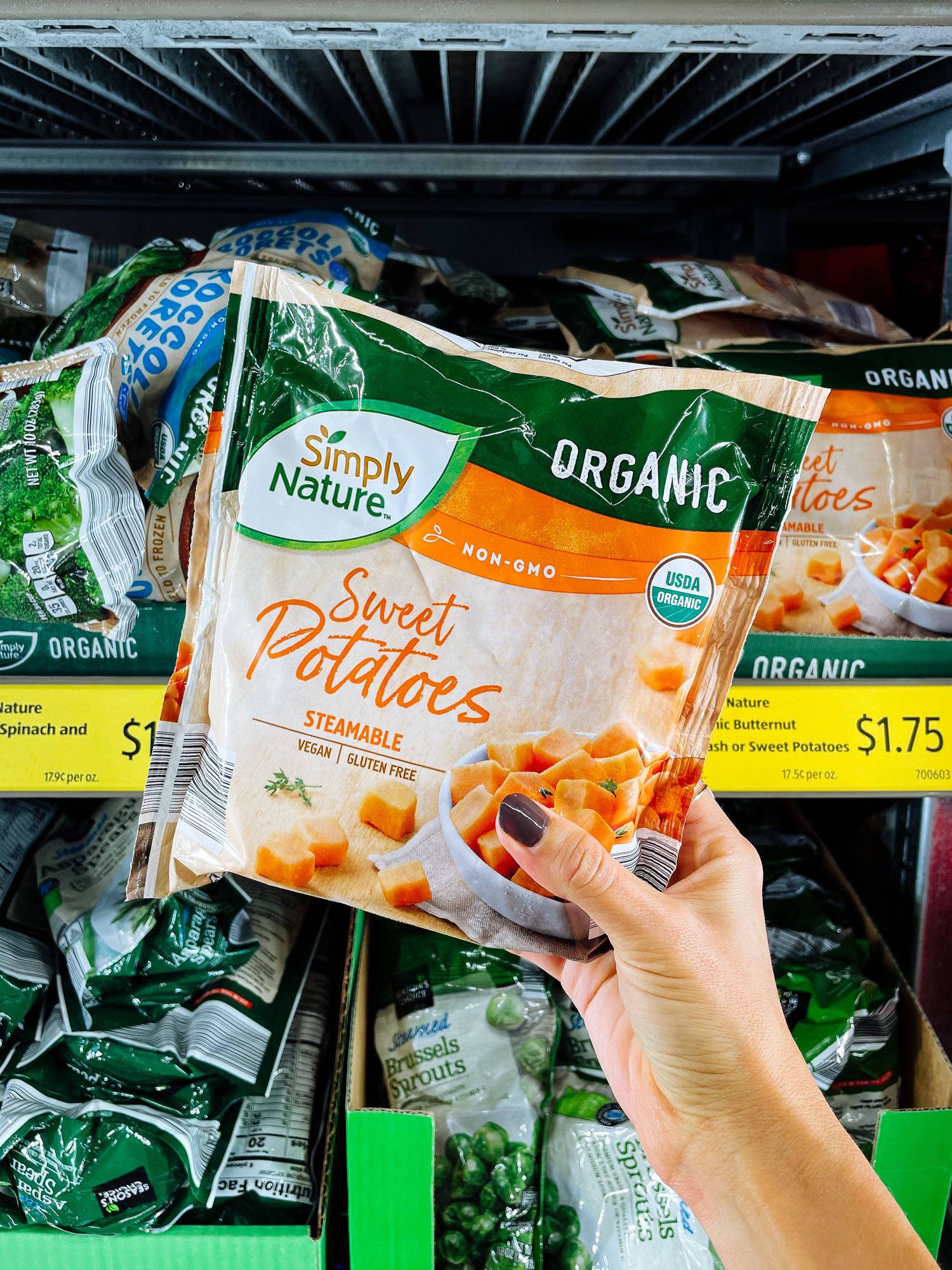 White hand holding frozen sweet potatoes from ALDI.