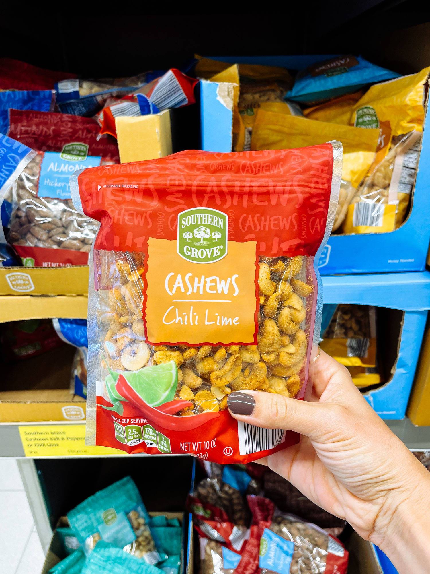 White hand holding chili lime cashews from ALDI.