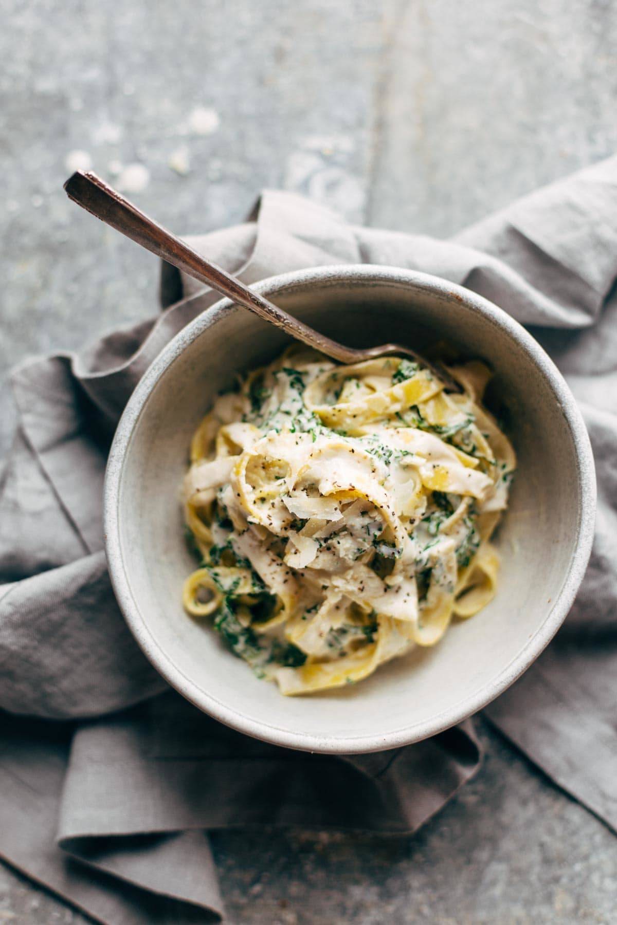 Kale pasta in a bowl with a napkin and a fork.