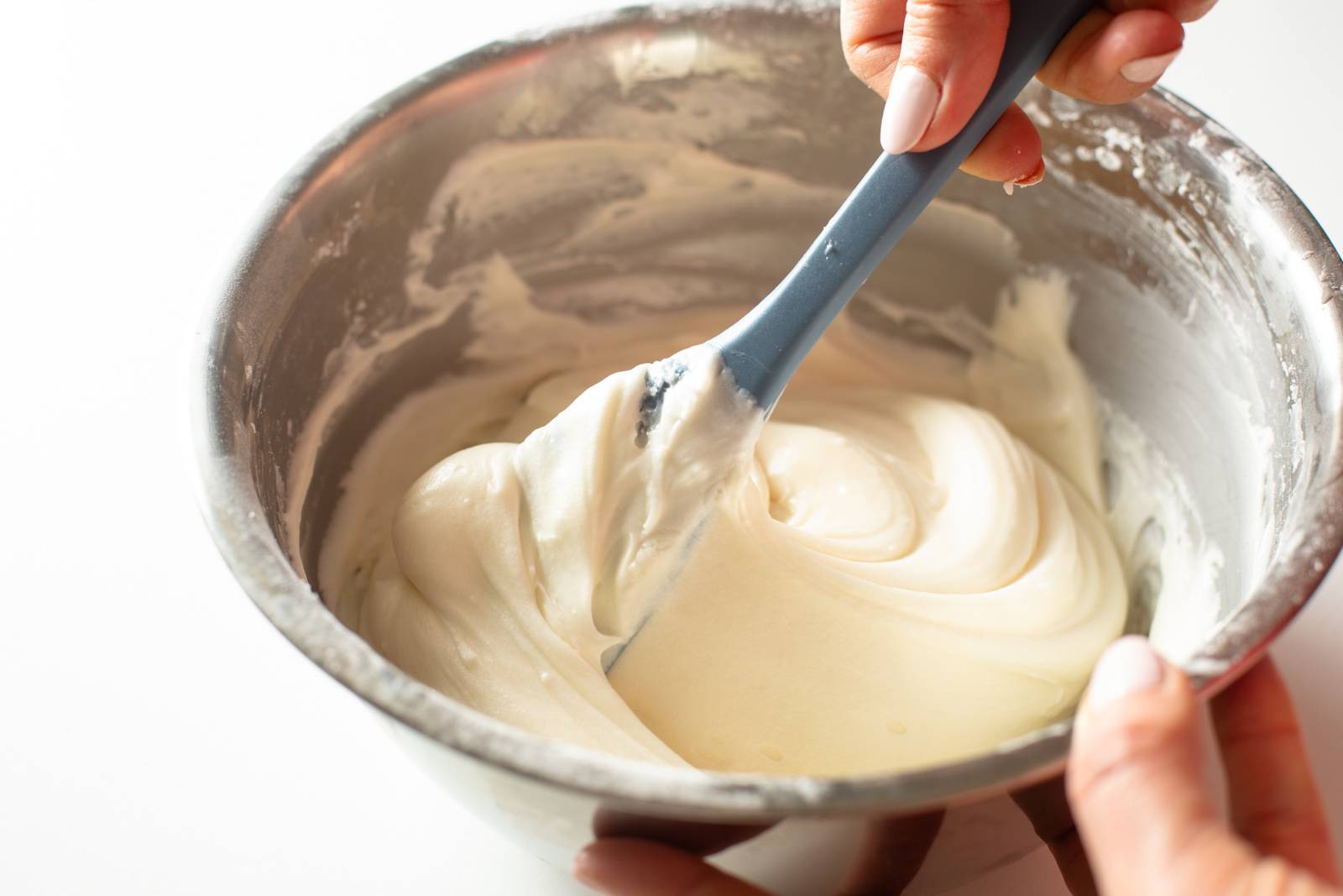 Mixing cream cheese frosting in a bowl.