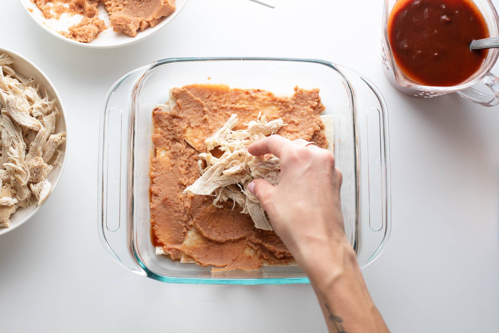 Layering beans and chicken for an enchilada casserole.
