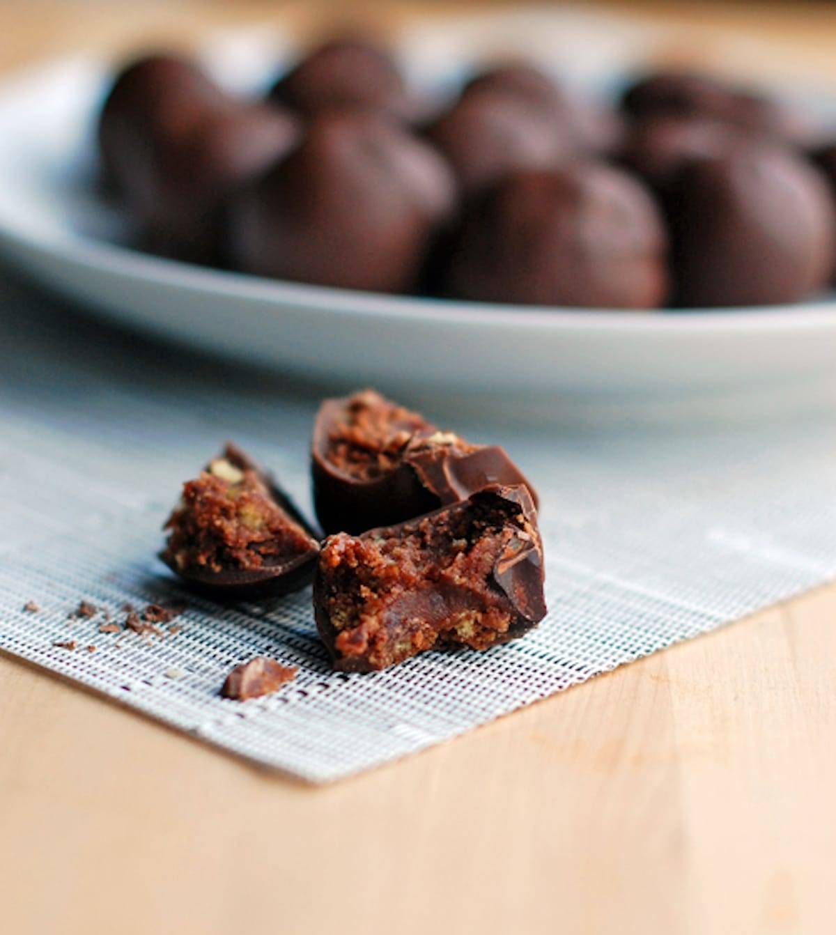 Triple chocolate party balls on a plate and one ball in pieces on a placemat. 