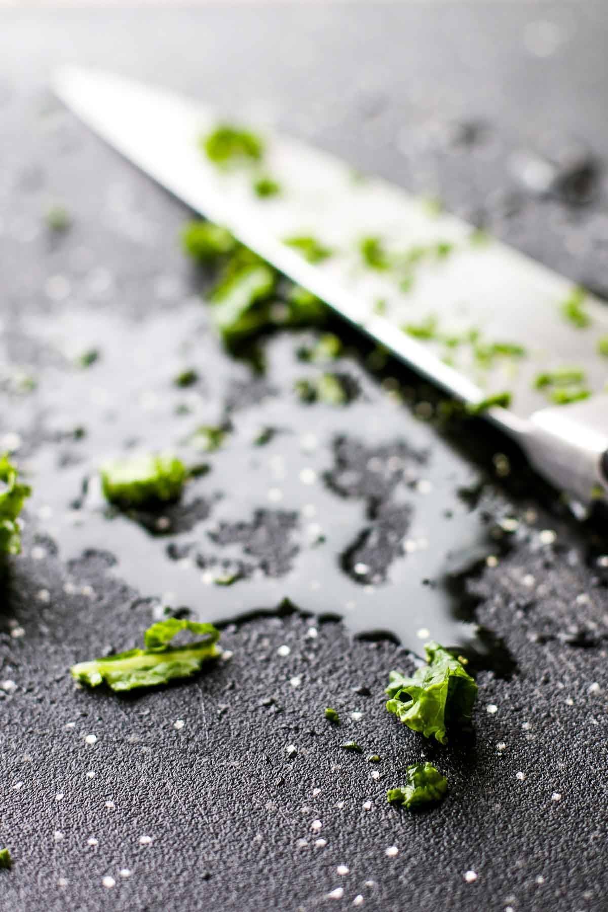 Herbs on a cutting board with a knife.